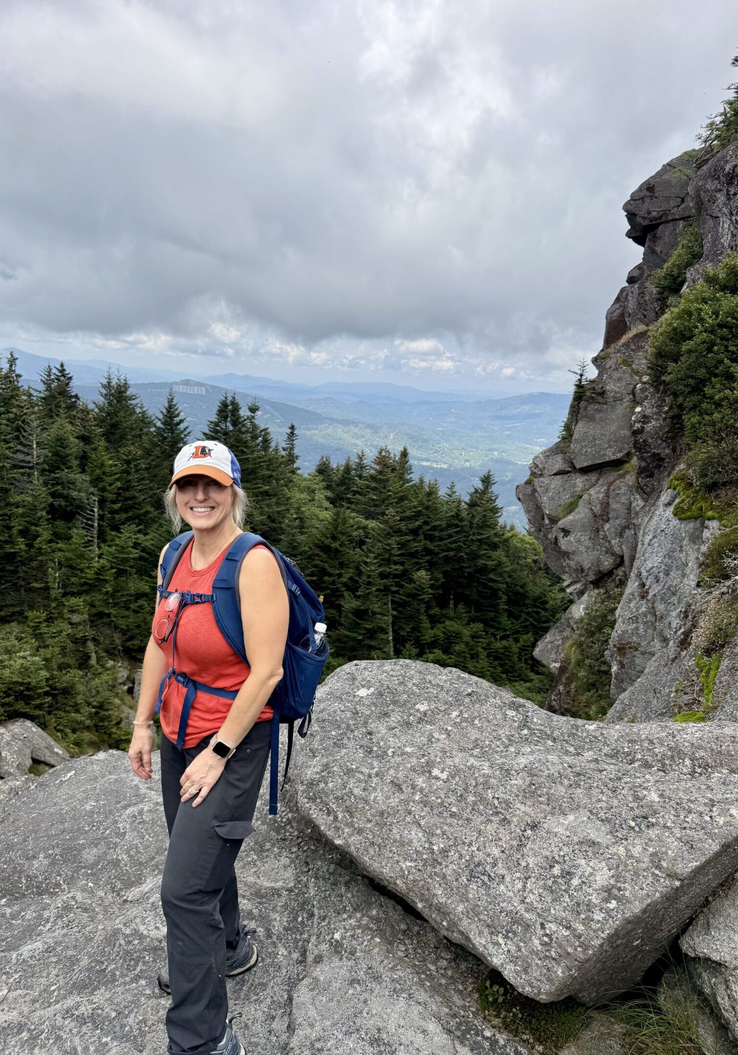 Woman hiking on a rocky trail with a scenic mountain backdrop.